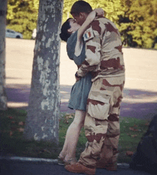 a man in a camouflage uniform is kissing a woman