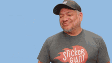a man wearing a shirt that says stick giant is pointing