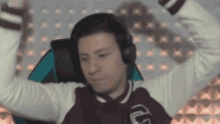 a man wearing headphones is sitting in a chair with his arms up in the air .