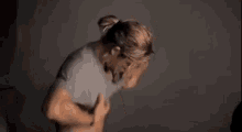 a man with long hair is taking off his shirt in a dark room .