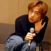 a young man is sitting on a couch holding a microphone in his hand