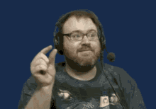 a man with a beard and glasses wearing headphones and a microphone is pointing up .