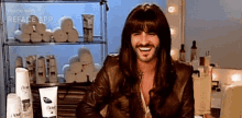 a man with long hair and a beard is smiling while wearing a wig and a leather jacket .