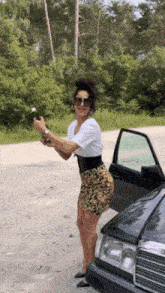 a woman is standing next to a car holding a bottle of wine