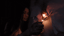 a woman looks at a person lighting a candle