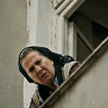 a woman wearing a black head scarf looks out a window