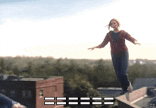 a woman in a red jacket is jumping off a ledge with the letters cc in the background