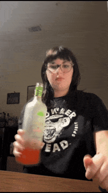 a woman wearing a black shirt that says killer head is holding a bottle