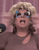 a woman in a pink and orange floral dress is talking into a microphone