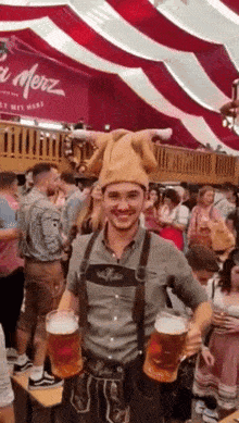 a man wearing a hat and overalls is holding two mugs of beer