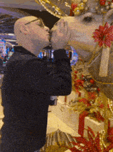 a man kisses the nose of a camel in front of christmas decorations