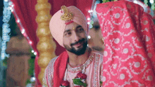 a man in a turban is standing next to a woman in a red dress .