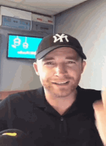 a man wearing a ny hat is smiling