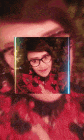 a woman wearing glasses and a red shirt is surrounded by a rainbow light