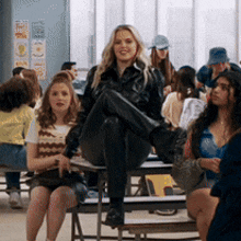 a woman is sitting on a bench with her legs crossed in a crowded room .