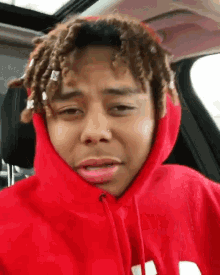 a young man wearing a red hoodie with the letter m on it