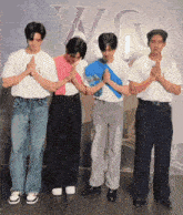 a group of young men are praying in front of a sign that says a