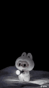 a stuffed animal is holding a flashlight in its hand in the dark .