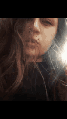 a close up of a woman 's face with a reflection of the sun in her hair