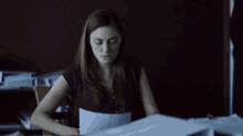 a woman is sitting at a desk looking at papers