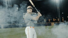 a baseball player holds a bat in front of a sign that says clemson