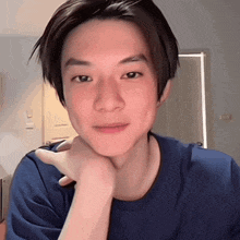 a young man in a blue shirt with his hand on his chin