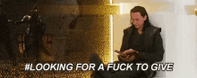 a man is sitting on a couch reading a book with the caption #looking for a fuck to give .