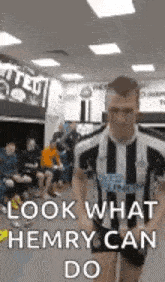 a man in a striped shirt is walking in a locker room and says `` look what hemry can do '' .