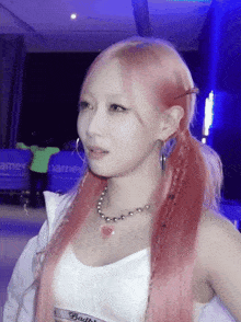 a woman with pink hair is wearing a white top that says baddie