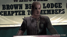 a man stands at a podium in front of a sign that says brown lodge members