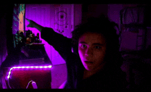 a person is standing in a dark room with purple lights behind them .