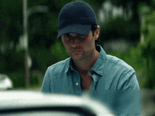 a man wearing a blue hat and a blue shirt looks down