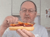 a man with glasses is eating a hot dog