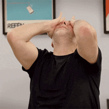 a man in a black shirt holds his hands to his face in front of a poster that says reff