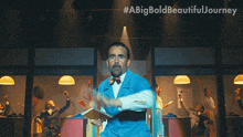 a man in a blue suit is jumping in the air with #abigbold beautiful journey written on the bottom