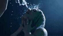 a woman with purple hair is drinking water from a glass