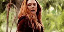 a close up of a woman with red hair in a forest .