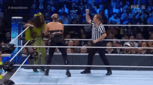 a referee is standing in the middle of a wrestling ring with two women fighting .