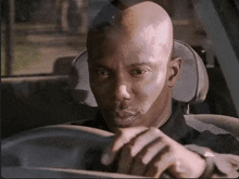 a bald man is sitting in the driver 's seat of his car