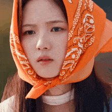 a close up of a woman wearing an orange bandana around her head