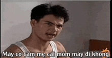 a man in a white tank top is making a funny face with a foreign language caption .