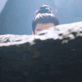 a man with a bun on his head is peeking out from behind a wall .