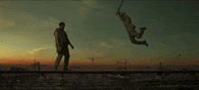 a man is standing on a bridge while another man is flying in the air