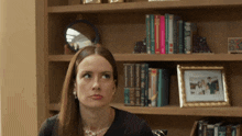 a woman is sitting in front of a bookshelf with a picture of a family on it