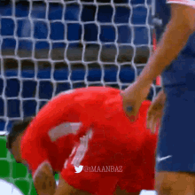 a man in a red shirt is holding a soccer ball in his hand ..