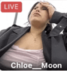 a woman is sitting in front of a sign that says live chloe moon .