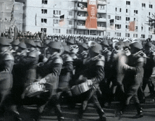 a black and white photo of soldiers marching in front of a building with a red banner that says " cccp "