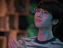 a young man wearing glasses is clapping his hands .