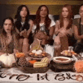 a group of women are sitting at a table with plates of food and a sign that says ' gno 1st baby '