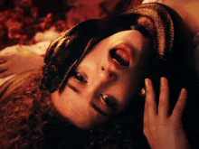 a woman laying down with a snake on her face